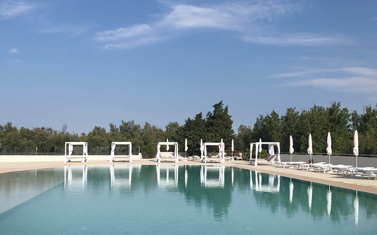 riqualificazione piscine del camping Rosapineta con adeguamento delle altezze del fondo e nuovo rivestimento, con bordo a sfioro, illuminazione subacquea e nuova pavimentazione color sabbia, nuove zone solarium con area vip e riqualificazione dell'area esterna del risto-bar