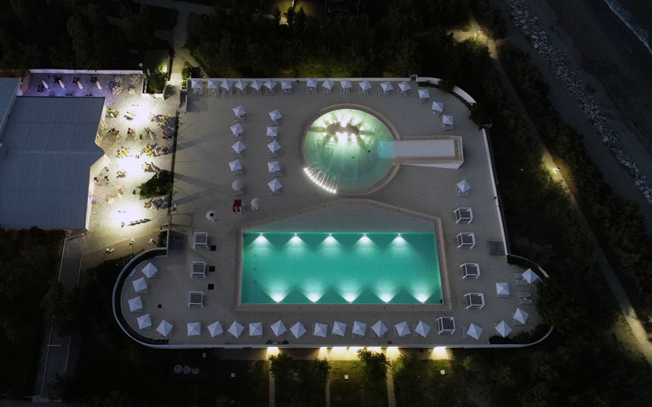 riqualificazione piscine del camping Rosapineta con adeguamento delle altezze del fondo e nuovo rivestimento, con bordo a sfioro, illuminazione subacquea e nuova pavimentazione color sabbia, nuove zone solarium con area vip e riqualificazione dell'area esterna del risto-bar