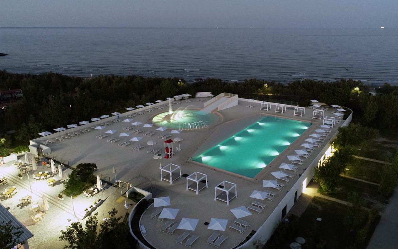 riqualificazione piscine del camping Rosapineta con adeguamento delle altezze del fondo e nuovo rivestimento, con bordo a sfioro, illuminazione subacquea e nuova pavimentazione color sabbia, nuove zone solarium con area vip e riqualificazione dell'area esterna del risto-bar